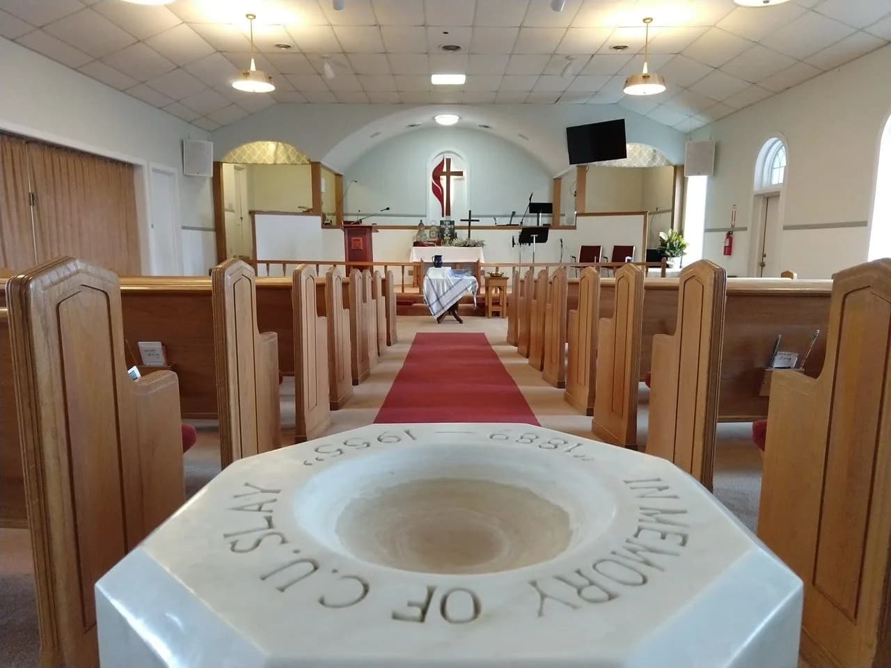 Empty sanctuary at Weaver First United Methodist Church, baptismal font in foreground, red carpet aisle leading to the altar
