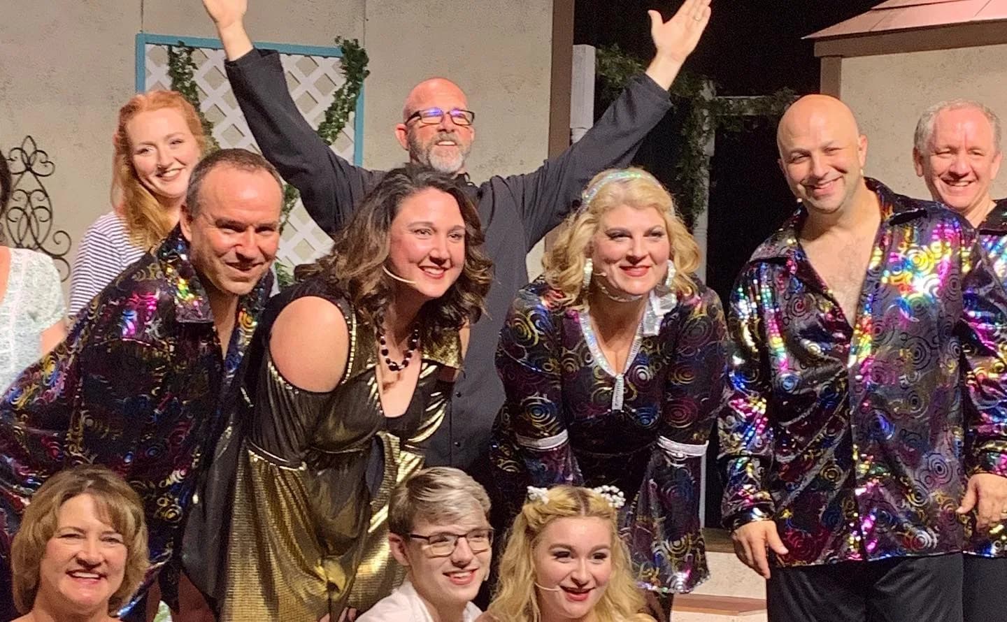 Jay Jenkins center-back in a community theater production, arms raised, surrounded by the cast in nun habits — including Judy Shealy and Scott Whitney