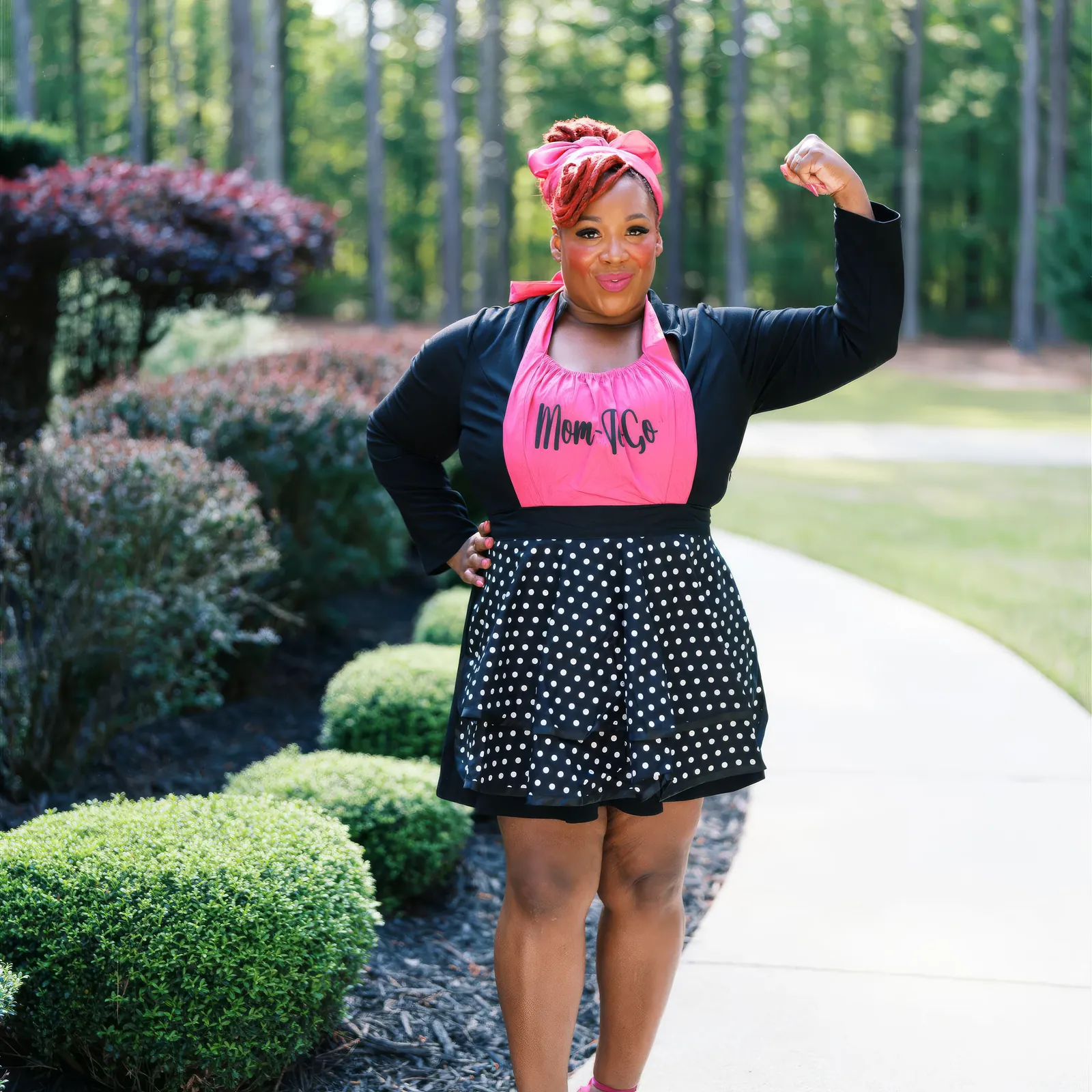 Jean Ellison in a pink Mom-To-Go apron, fist raised, outdoors in Anniston