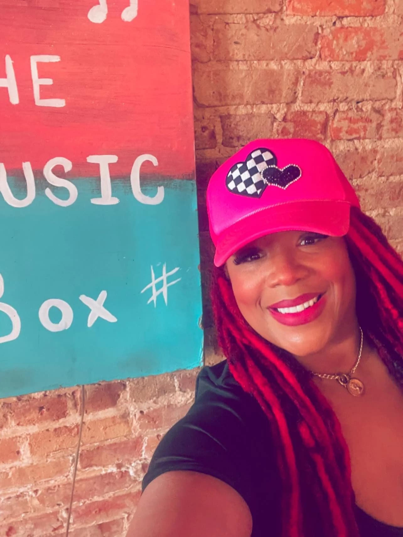 Jean Ellison in a hot pink hat in front of The Music Box sign in Anniston
